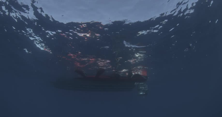 A boat has people's legs hanging off the side above