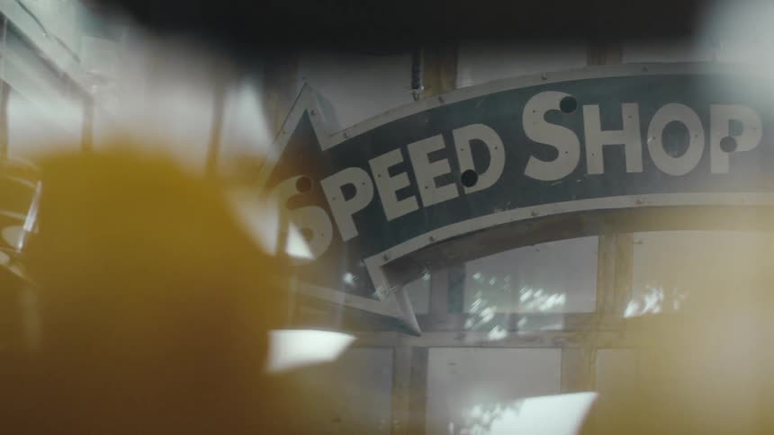 A vintage sign with partially obscured text in bold letters mounted on a building with large windows