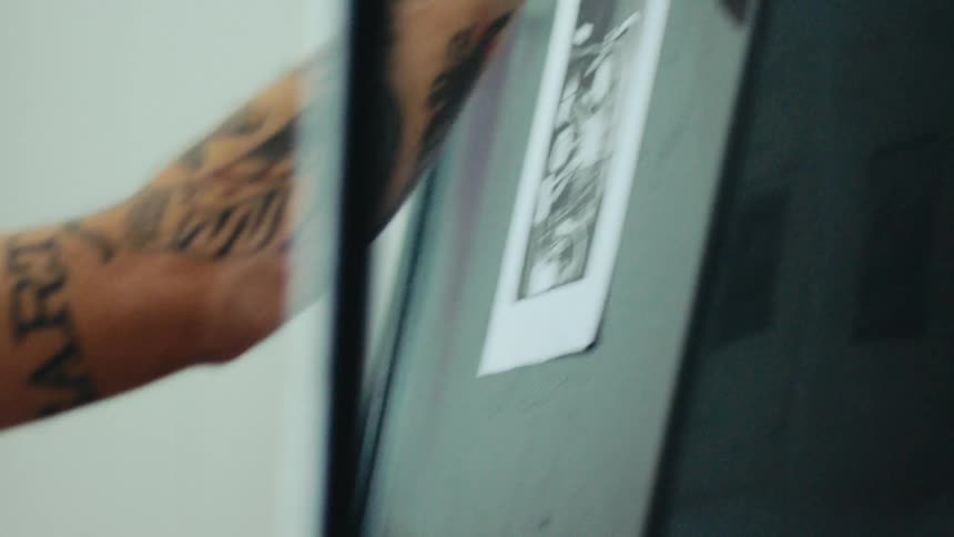 A person with tattoos on their arms is fixing a picture in a frame using a roller