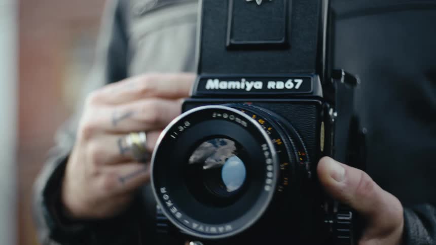 The lens of a mamiya rb67 camera held by a man