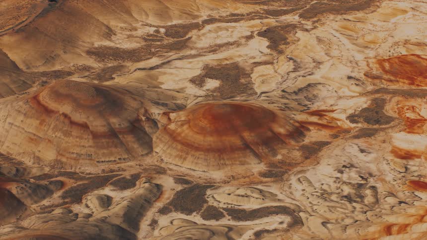A detailed aerial view of a desert landscape with two prominent circular reddishbrown geological formations