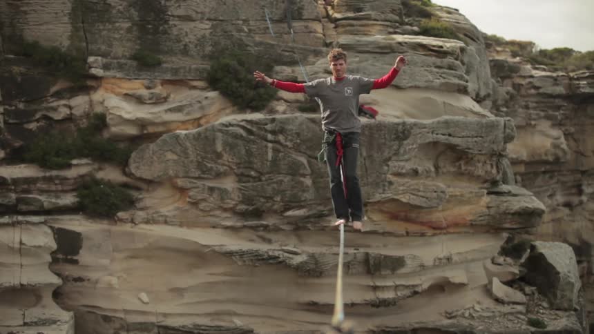 A man balances on a tightrope in a canyon