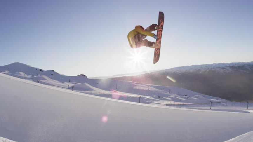 Man doing jumps off a slope on a sunny day