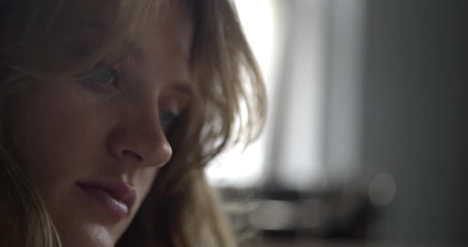 A blonde woman tilting her head while she looks at something before straightening her head