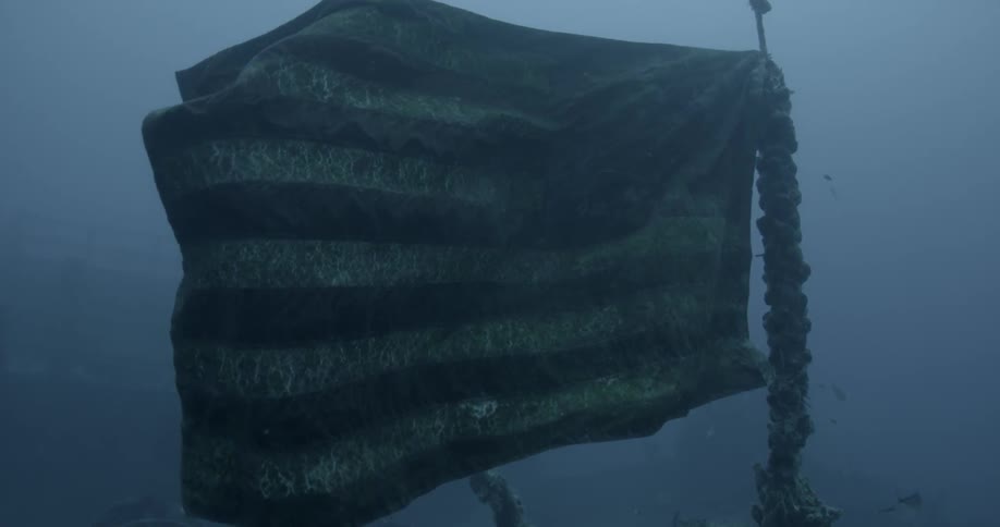 An american flag floats on ship wreckage in the ocean