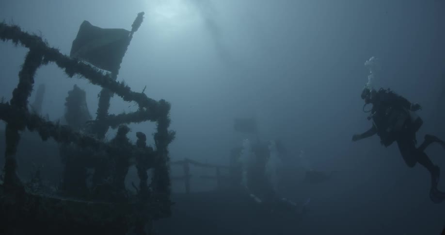 A old shipwreck is filmed by 3 divers