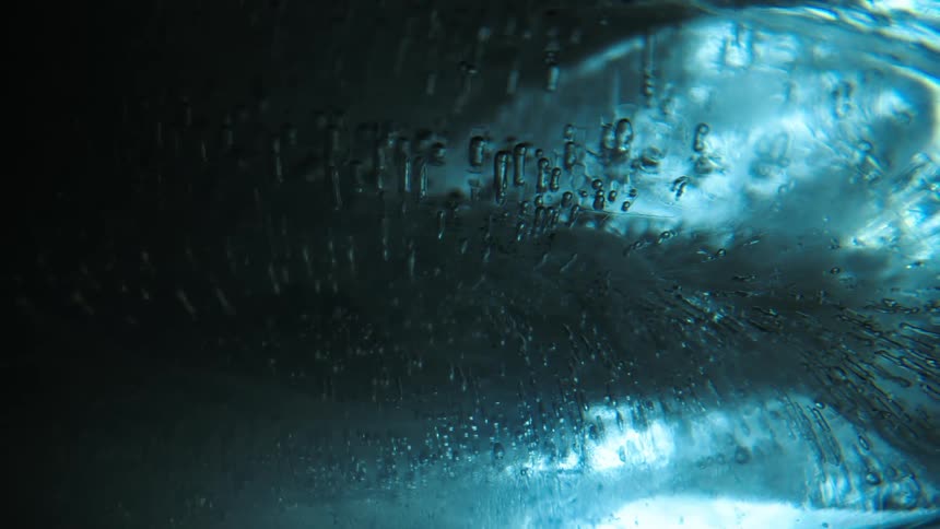 The intricate patterns of ice crystals and air bubbles illuminated by a cool blue light creating a mesmerizing abstract texture
