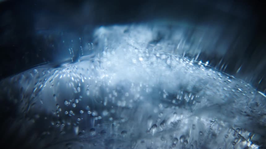 A macro shot of ice featuring trapped air bubbles creating a textured and abstract visual effect under cool bluish lighting