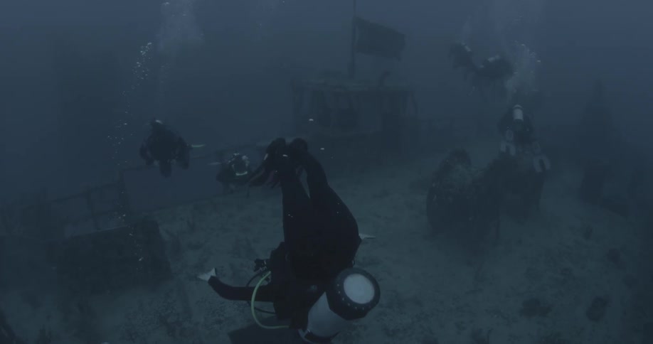 Divers swim near ship wreckage in the ocean