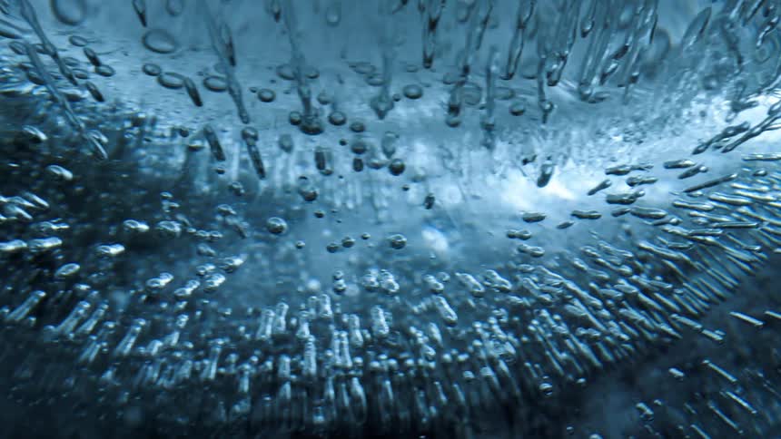Blue tinted ice showcases numerous air bubbles and elongated ice formations creating a textured and dynamic pattern