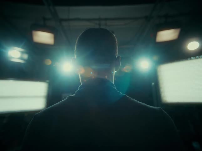 Person stands facing multiple studio lights and gestures