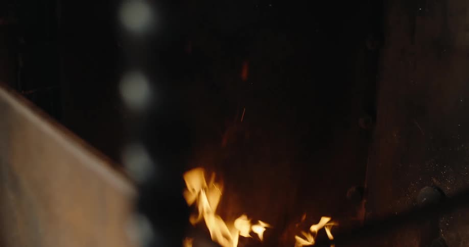 Person moving nearby casts a shadow onto a fire burning inside a metal walled enclosure