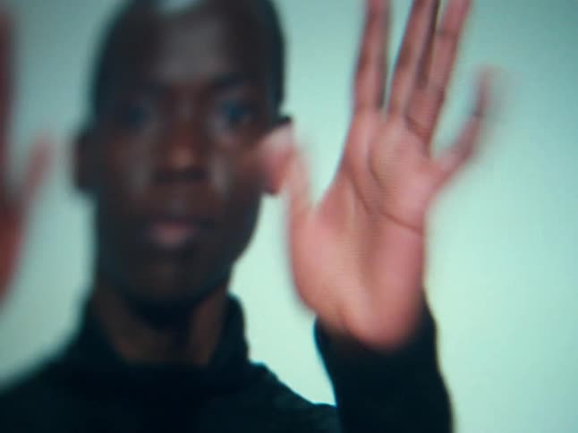 Closeup of a woman on a television screen raising their hands