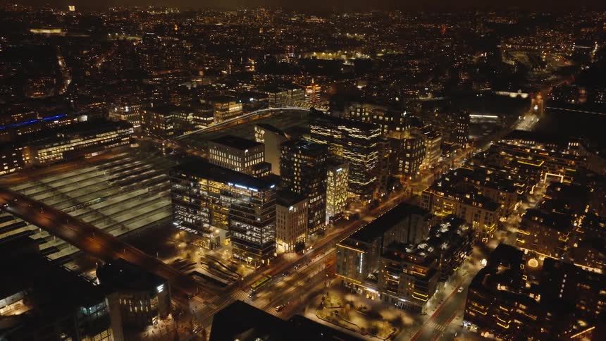 Traffic travels along brightly lit downtown streets at night