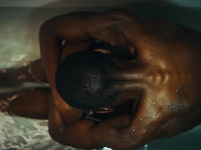 A woman in the bath tub shows her back and tattoos