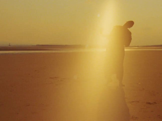 Silhouette of a person on the sand of the beach opening their arms