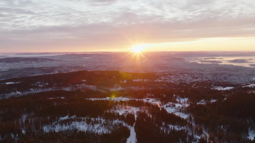 A suburb sits outside a snowy forest at sunrise