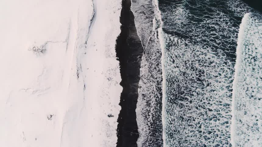 Aerial view of a sea with waters reaching the coast with snow