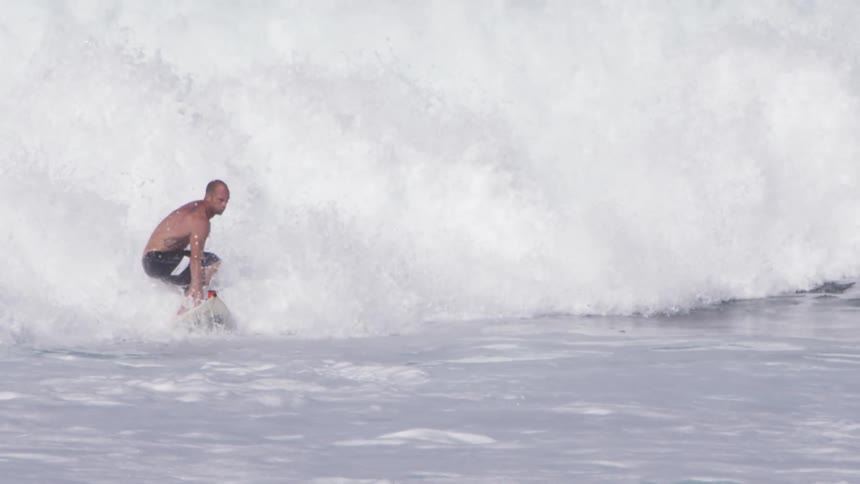 A man is riding town a wave on his surfboard