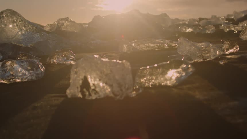 A landscape dotted with jagged chunks of ice under a twilight sky with scattered clouds at sunset