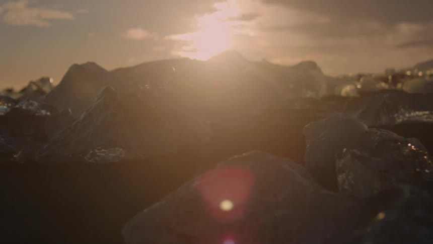Black sand with ice and the sun on the horizon