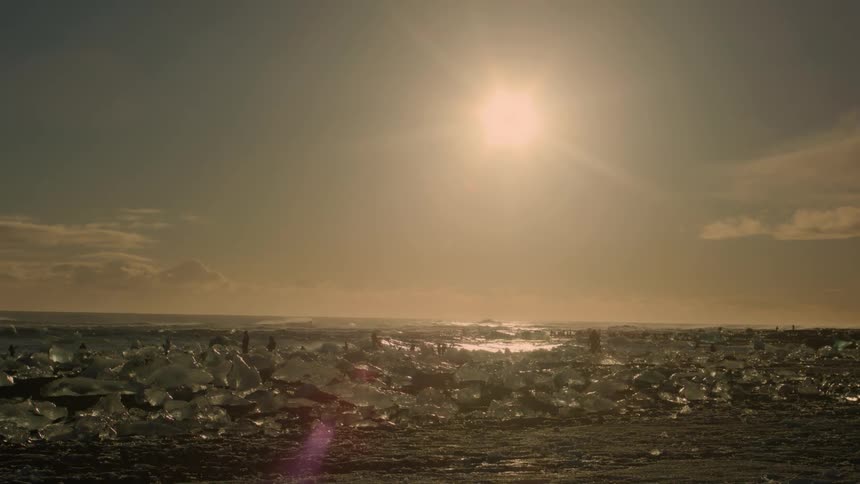 Landscape of a beach with ice blocks and the sun in the background