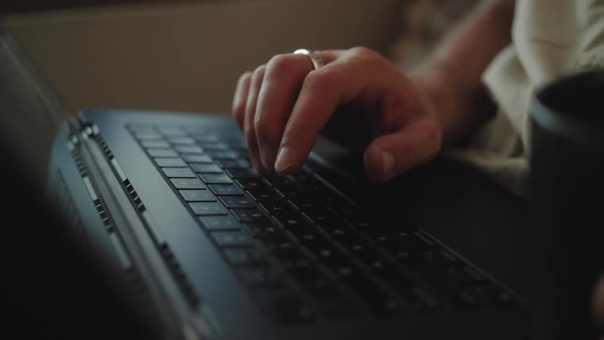A persons fingers typing on a black laptop keyboard