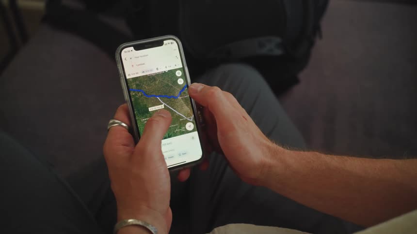 A persons fingers moving a cell phone screen where there is a map with a blue line