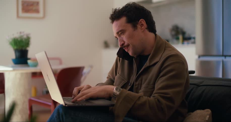 Man sitting talking on cell phone and typing on laptop