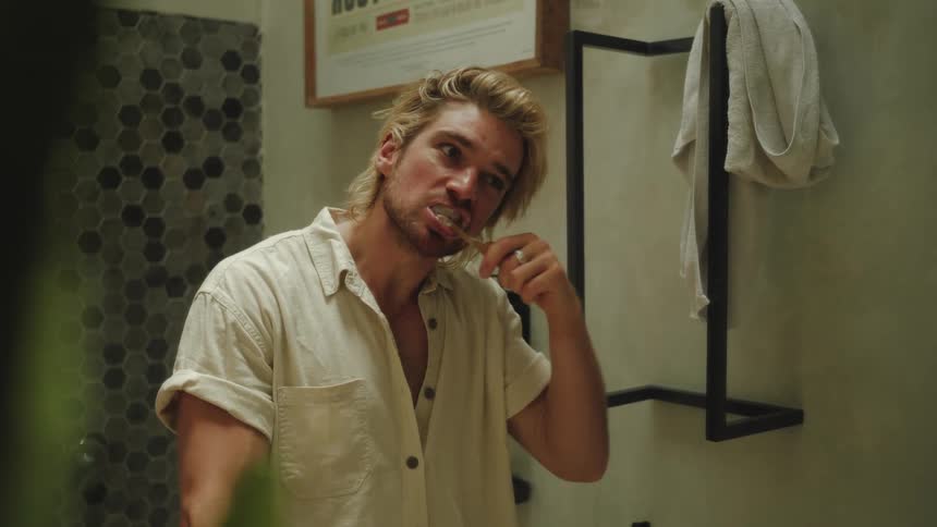 Man brushing his teeth in front of the mirror
