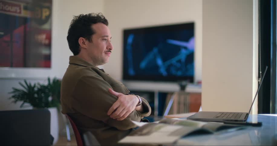 Man watching a laptop screen types a key while sitting in the office