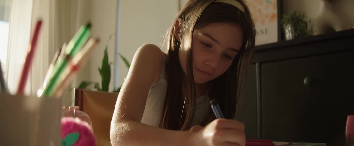 Girl writing in a notebook in a room of the house