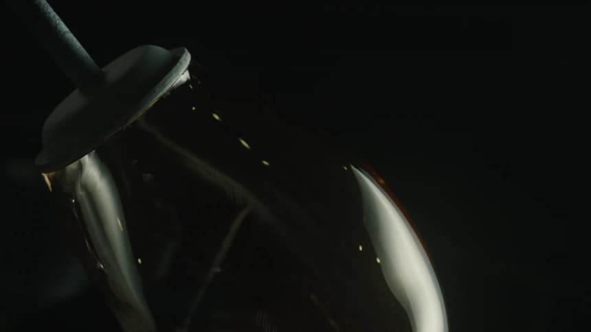 A glass vase is rotated against a dark background capturing the glassblowing process