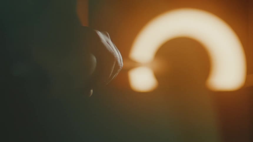 A close up of a hand turning a handle connected to a vessel inside a hot furnace