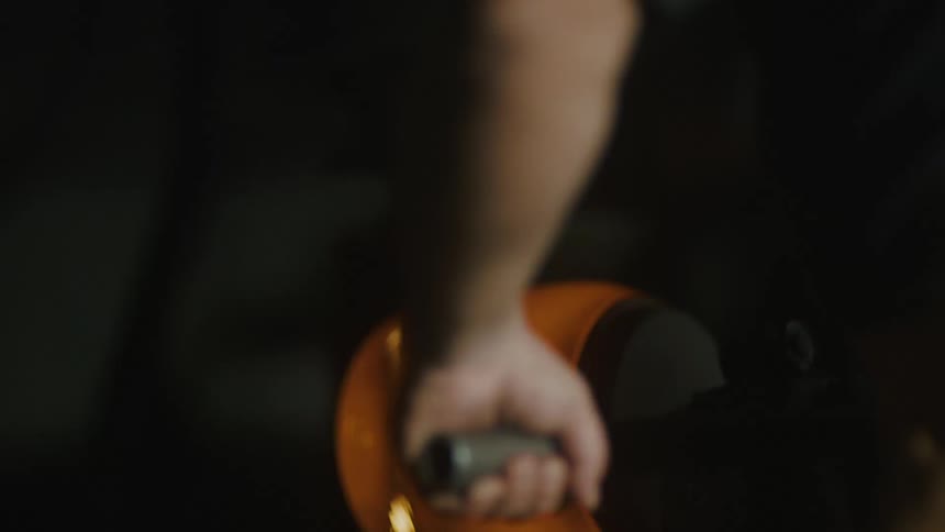 A piece of molten glass is being shaped by hand capturing the glassblowing process