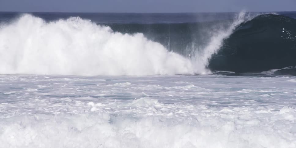 Person surfing underneath large ocean waves