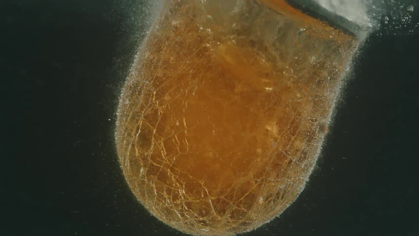 A melted glass bright orange in color due to the heat is under water and releasing several bubbles