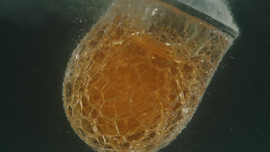 Closeup of a goldenhued molten glass block being shaped