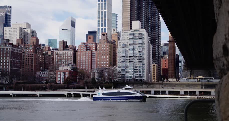 Recreational boat passing under a bridge on a waterway on the edge of a metropolis