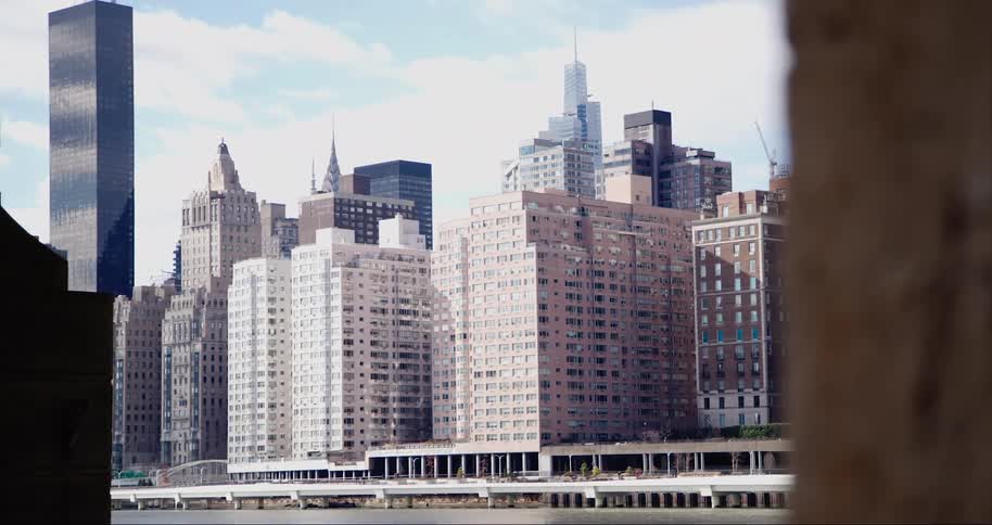 A cityscape with a variety of highrise buildings set against a partly cloudy sky