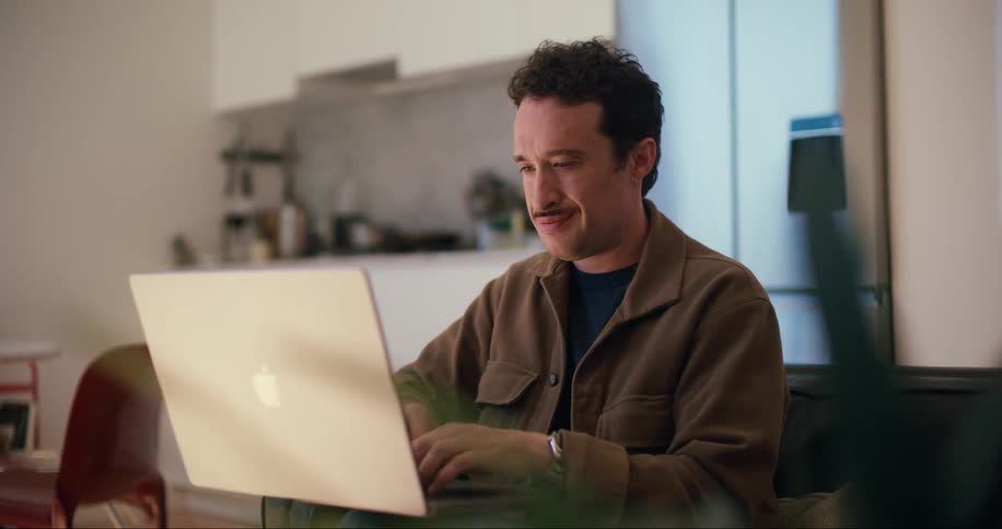 A man witting on the couch at home working on a laptop
