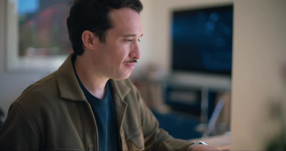 Man sitting at a table looking at a magazine with projects next to a laptop
