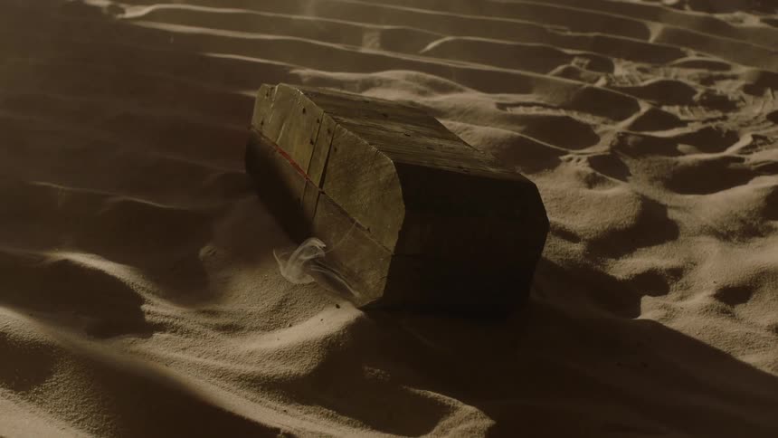 A clip of a wooden coal on a sandy surface