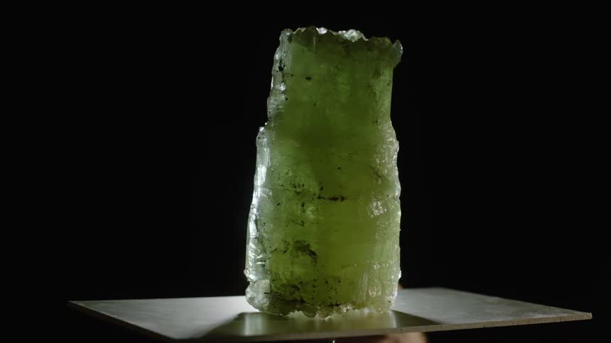 Jade crystal on display rotating on metal platform against a black backdrop