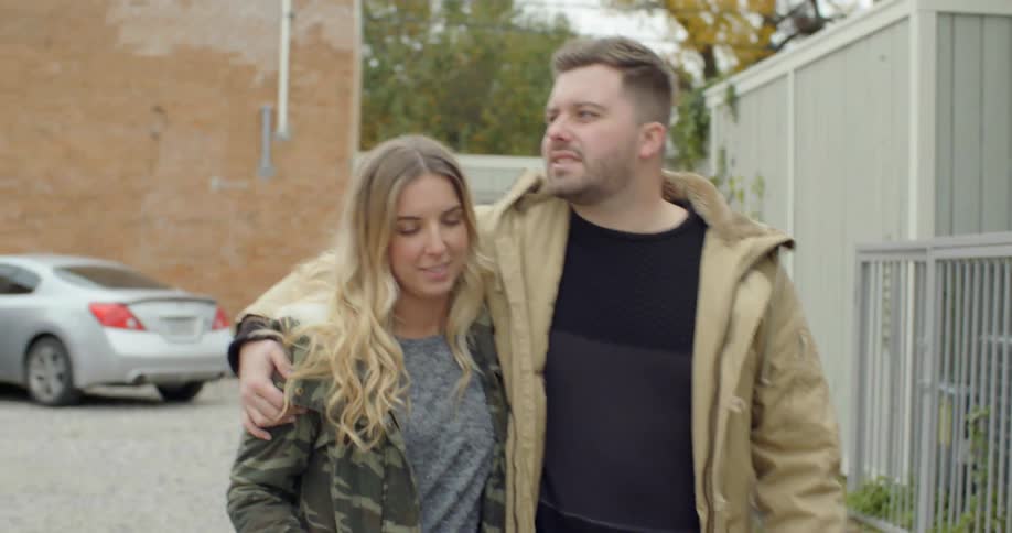 A man and woman are hugging as they walk down a street