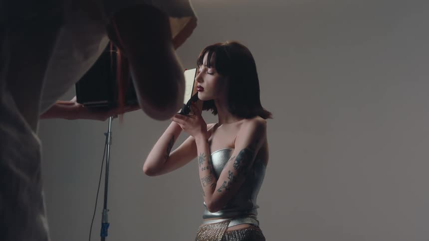 Professional photographer taking photo of a young woman in a studio