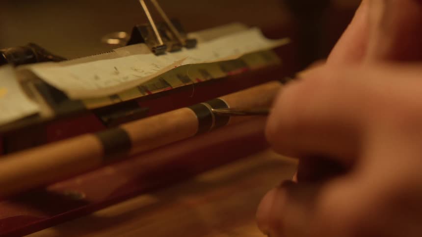 A person is sharpening a needle with a rolling machine
