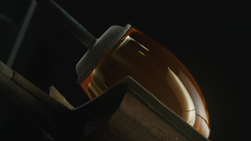 Glass is being cooled on a rod and shaped at the same time