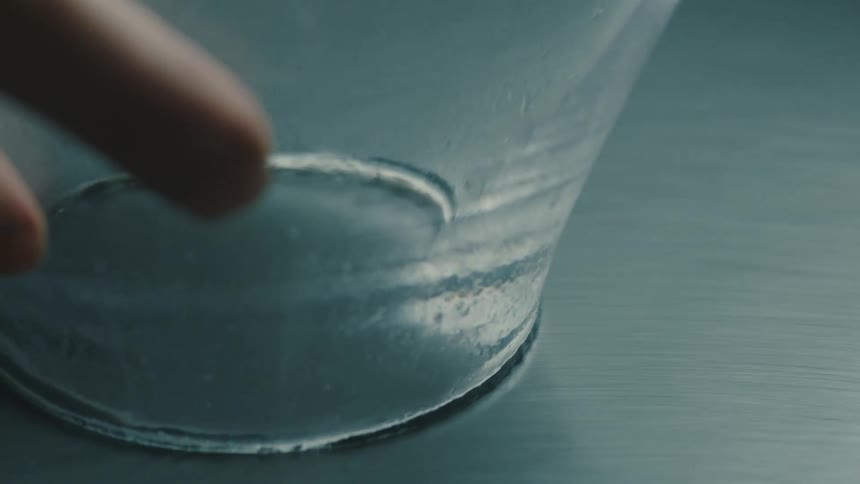 Pair of hands holding a glass cup against a surface