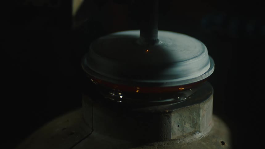 Close up of a tool rotating and producing glass